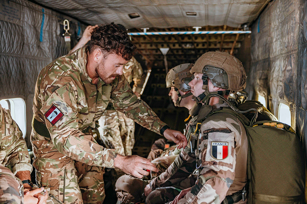 Instructor led training. Inside the airborne aircraft the parachutists prepare for a jump while instructors landing check their kit.